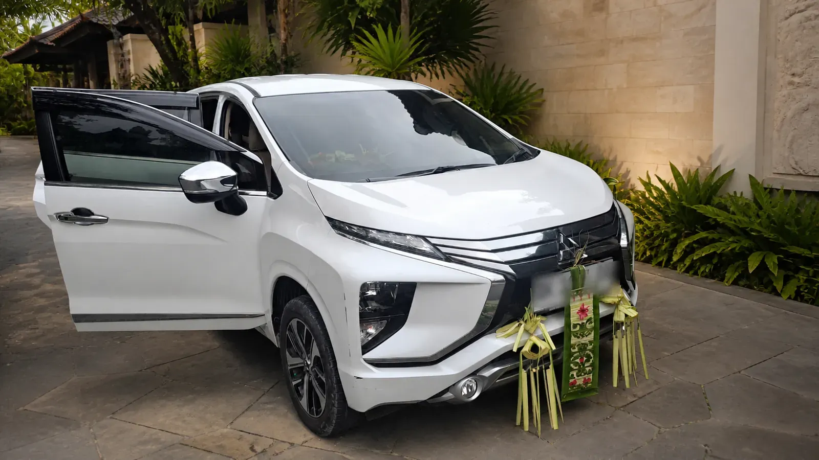 White Mitsubishi Xpander with Balinese decoration at a resort driveway